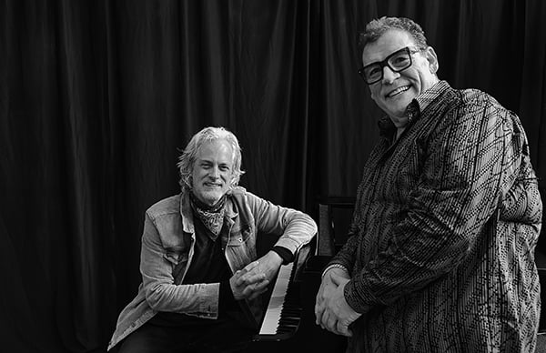 Scottie Miller, seated, and Tom Hunter, standing, beside a grand piano