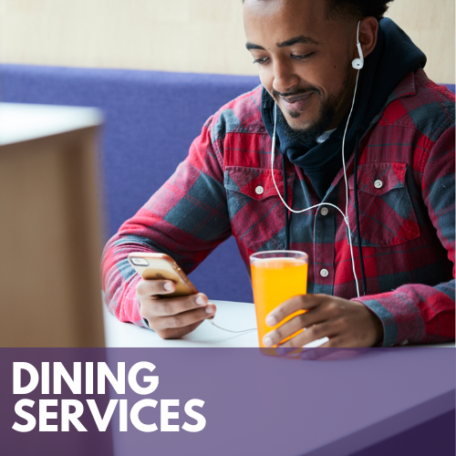 Male student sitting at a both in the University Dining Center with a beverage while looking at his phone