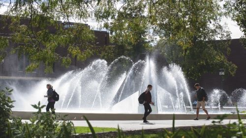 three people walking in front of the fountain, located behind the Centennial Student Union