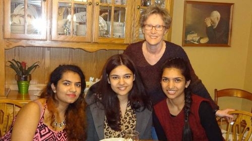 Three CELP students posing with a lady at a table for the Friendship Family Program