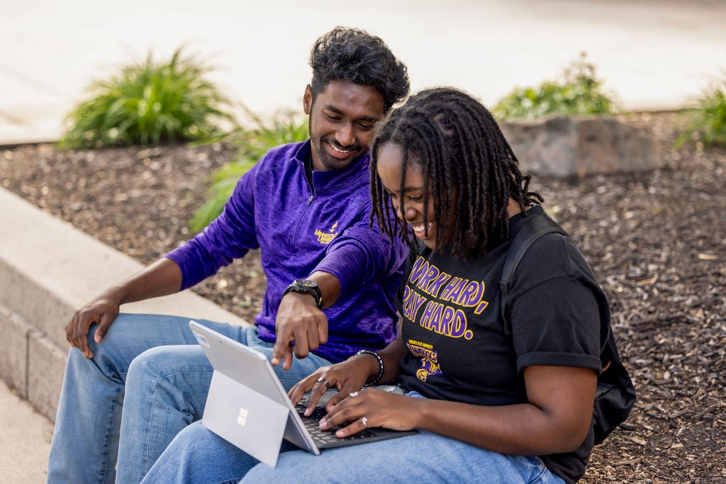 Two MSU students looking at a laptop and laughing. 