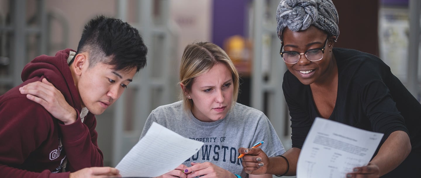 A female student helping two other students with their assignment