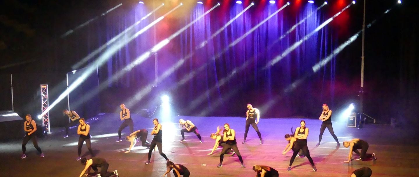 A group of female Maverick dancers performing on stage in the Performing Arts building during a lip sync contest