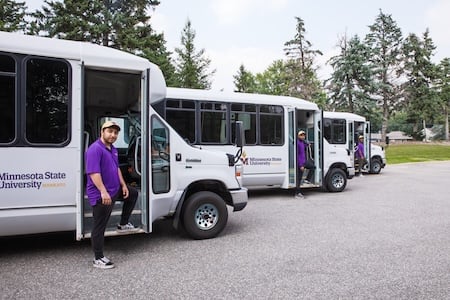 3 Night Time Shuttle bus drivers standing with their shuttles