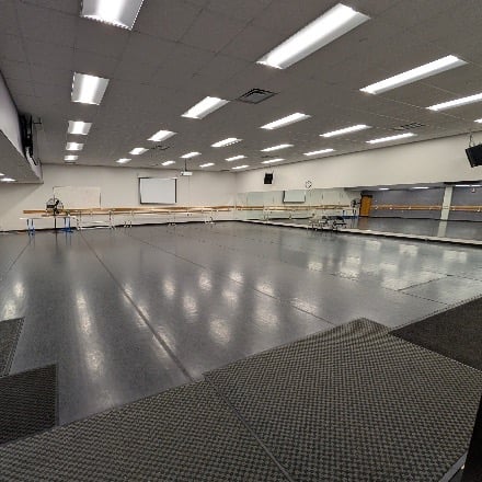Open dance studio with dance bars along one wall and dance mirrors along the other.