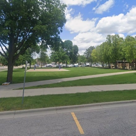 Open yard on MSU campus with sand volleyball court, green grass, and trees.