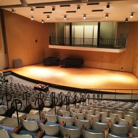 Large stage in front with lighting and seating rising towards the back.