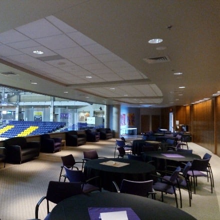 Room with tables and chairs and a window to view basketball court below. 