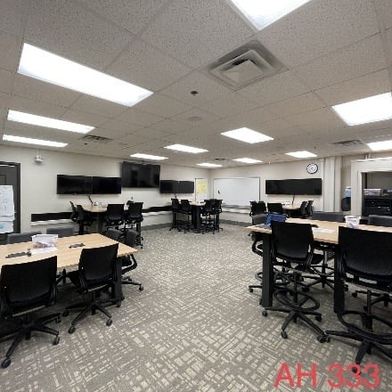 Classroom set up with groups of tables and chairs. 