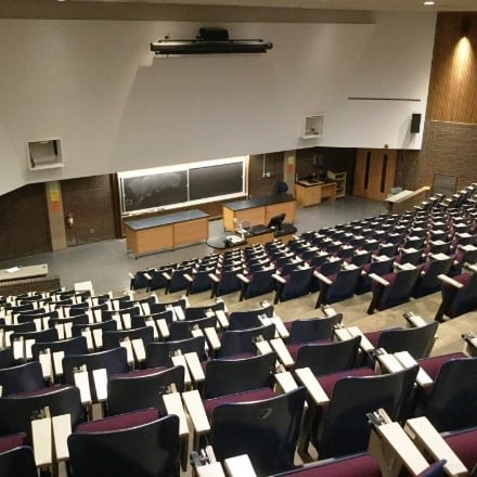 Auditorium with a large screen in front and chairs filling the room.
