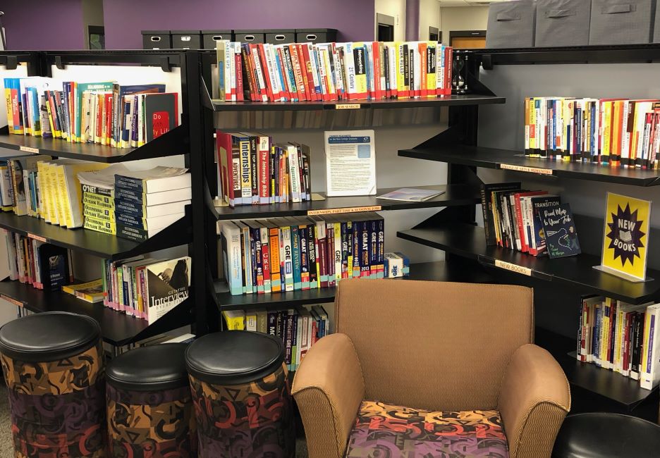 A chair and foot rest with shelves filled with books in the Career Resource Library