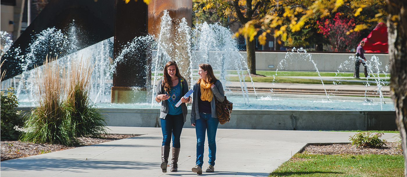 two women walking in front of a fountain