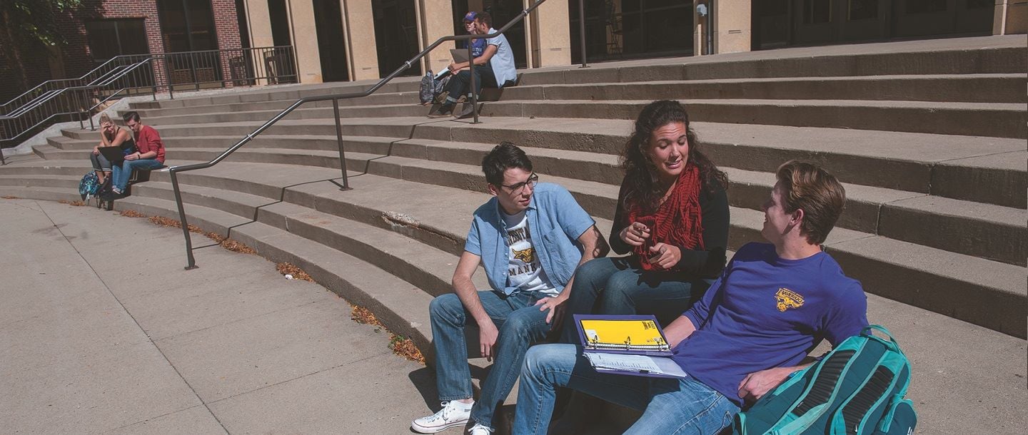 students sitting on a staircase infront of the university theatre