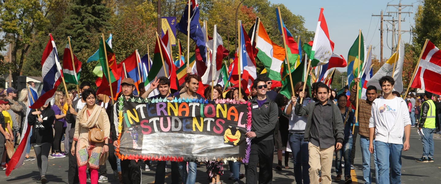 International students walking in a parade holding a banner that says international students 