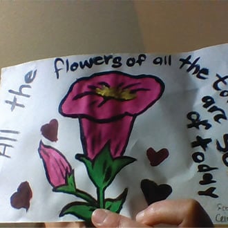 a hand holding a piece of paper with a flower and words