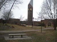 The park bench donated by the Minnesota State Mankato Faculty Wives in celebration of their 50th anniversary with the Bell Tower and Arch in the background