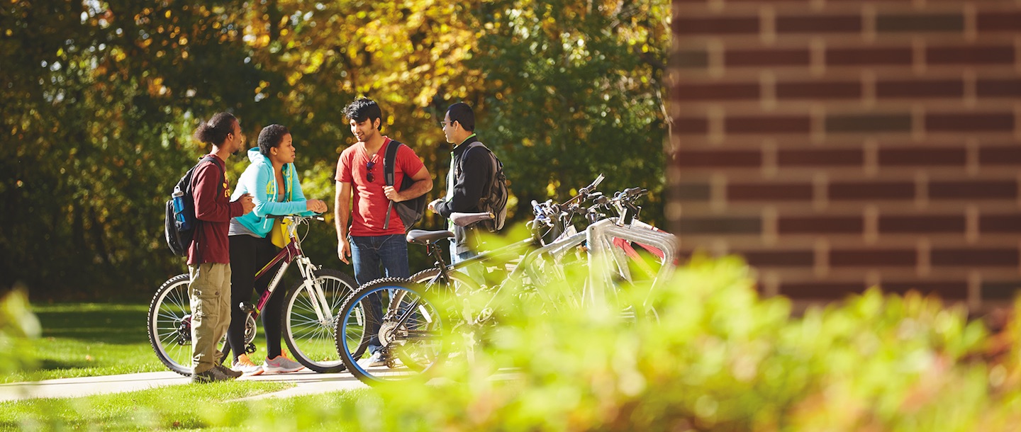 Students talking by a bike stand with multiple bicycles