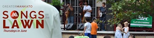 People at Songs on the Lawn, with the words Greater Mankato SOngs on the Lawn Thursdays in June over the top