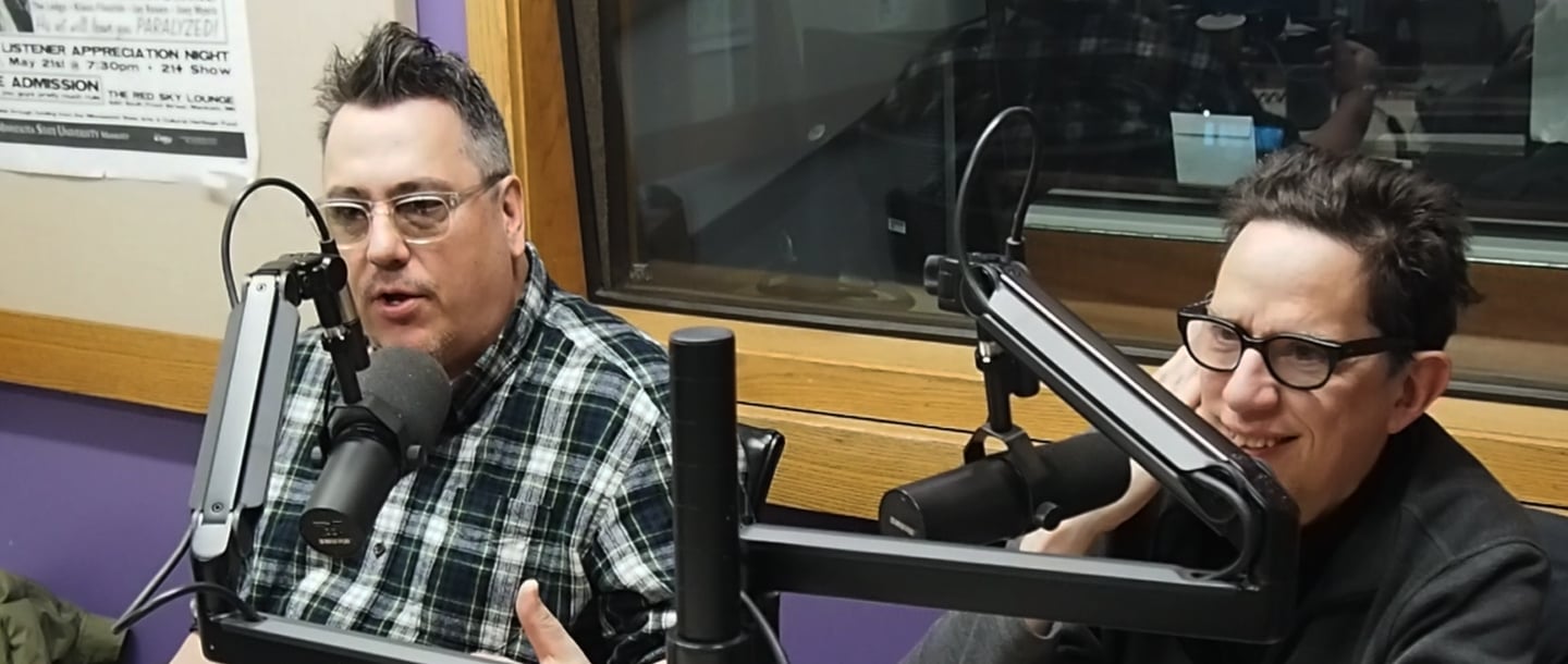 Two poeple speaking into microphones inside the KMSU Radio station studio