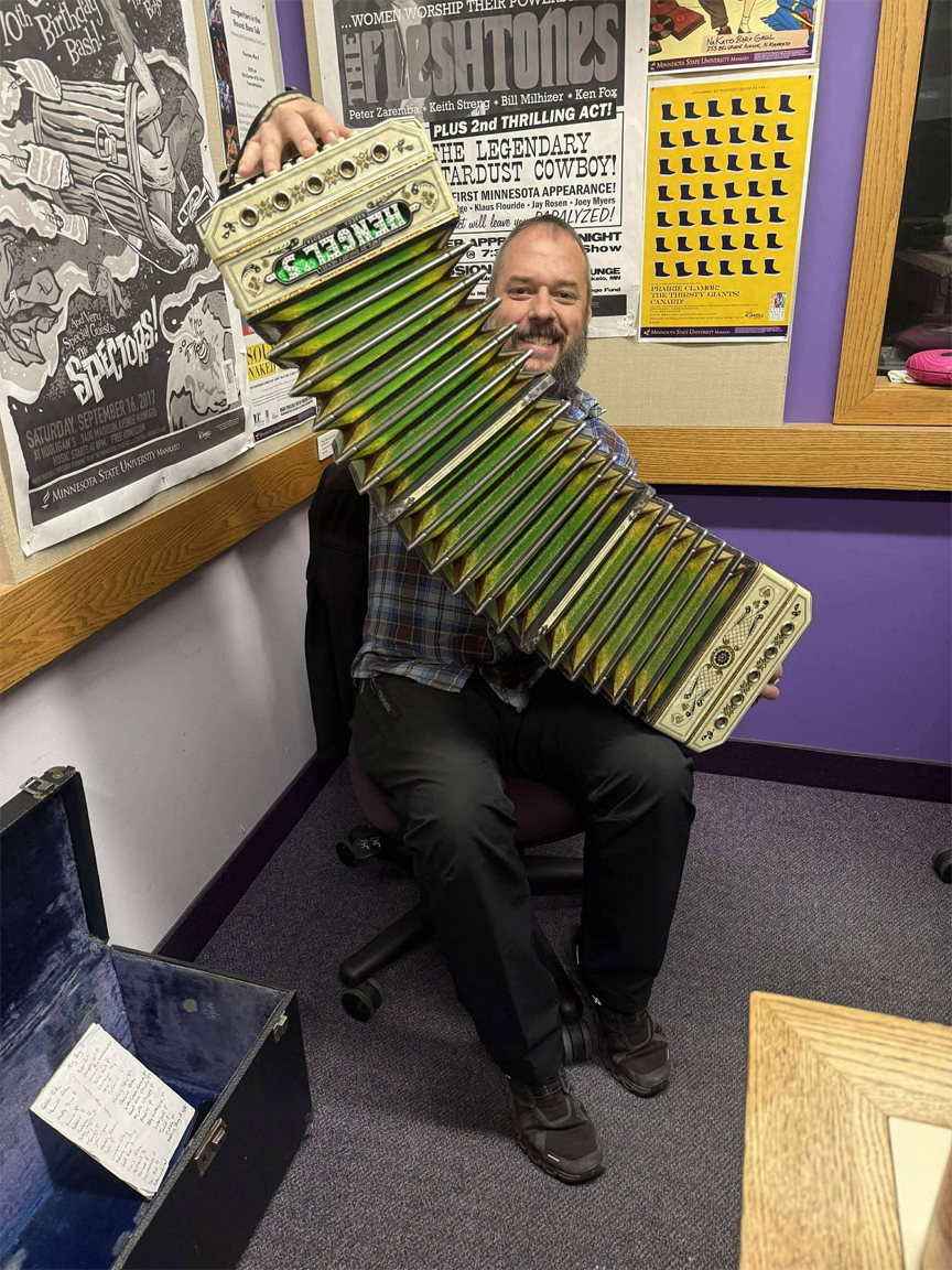 Concertina player Tom Moran holding a fully extended Christy Hengel concertina