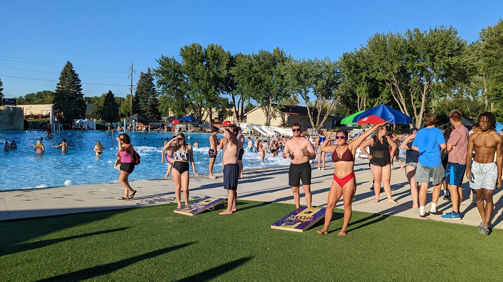 a group of people standing on grass near a pool