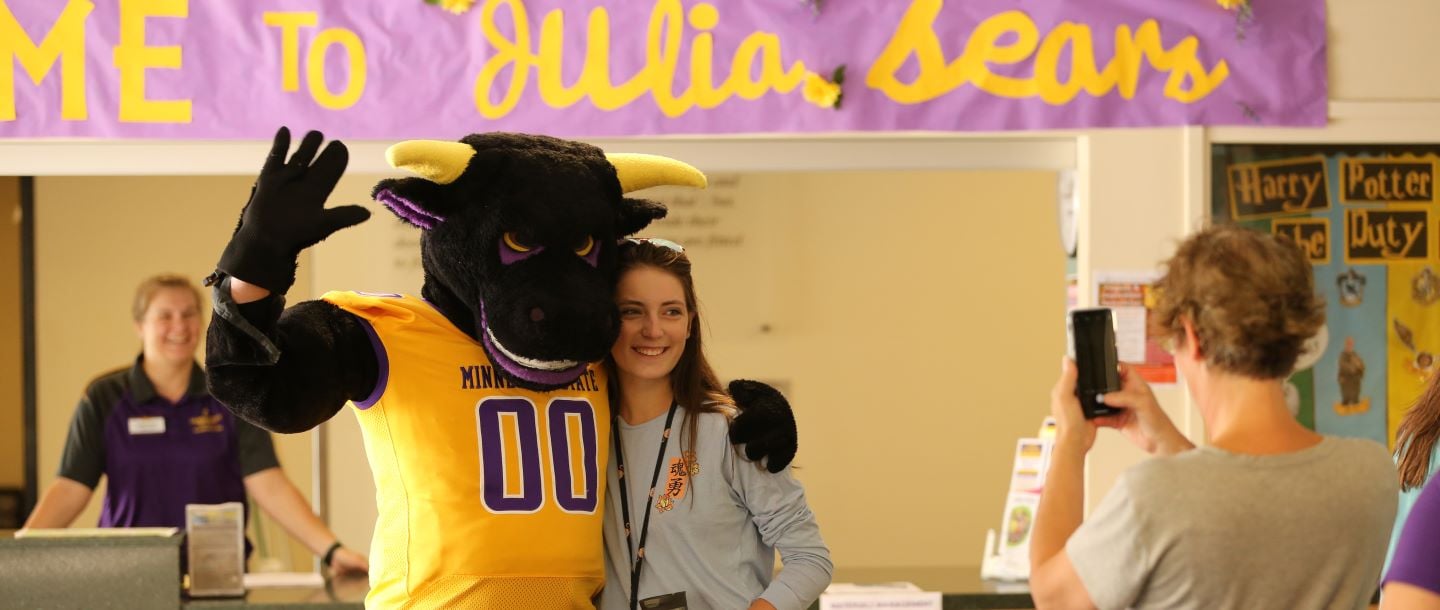student posing to take picture with the Minnesota State Mankato mascot mascot stomper