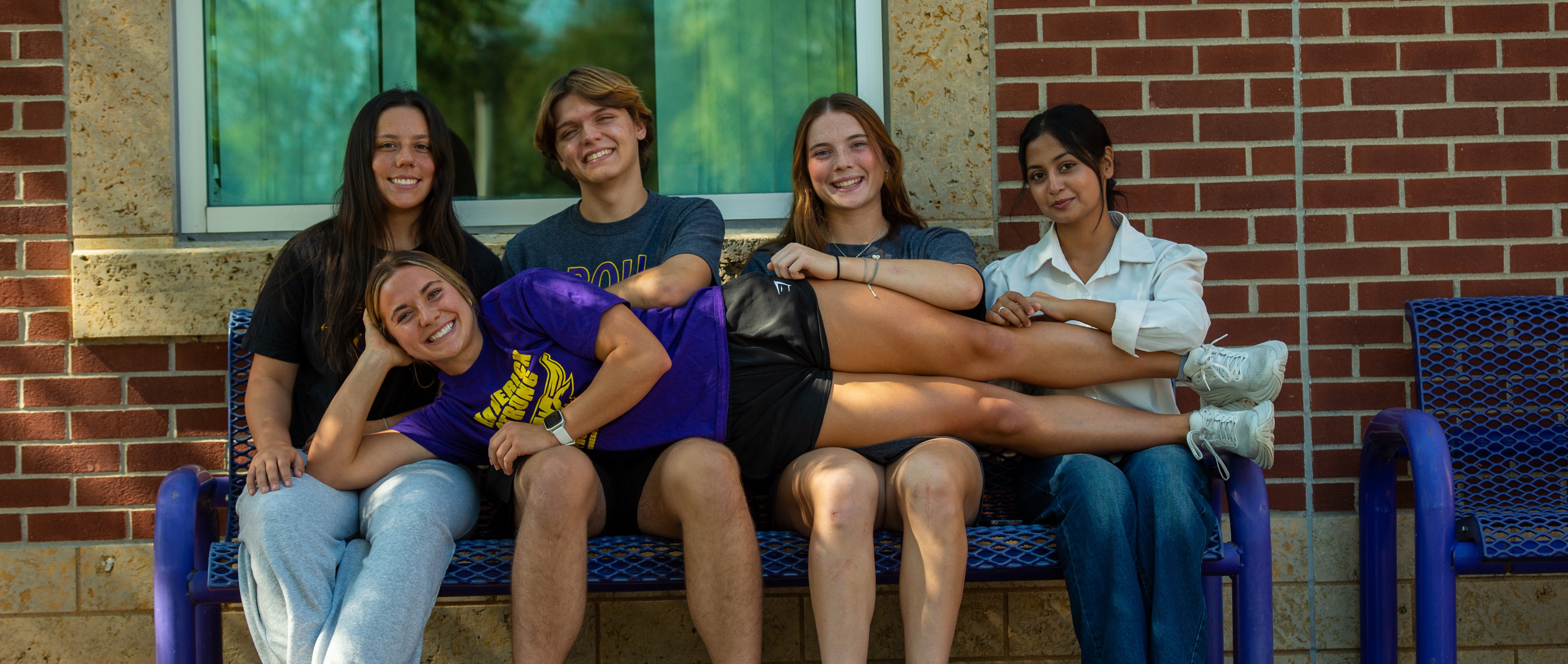Students sitting on a bench and posing for the camera