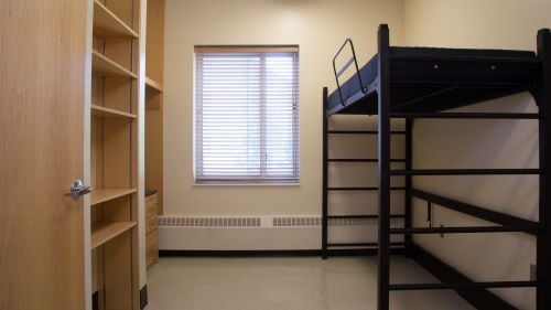 Photo inside a single semi-suite with a bed and shelving units
