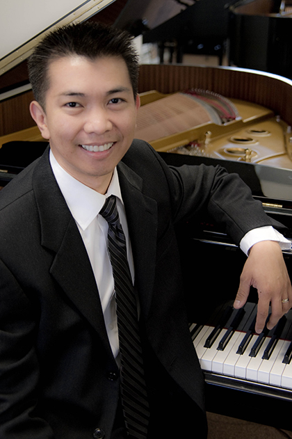 a person in a suit and tie sitting at a piano