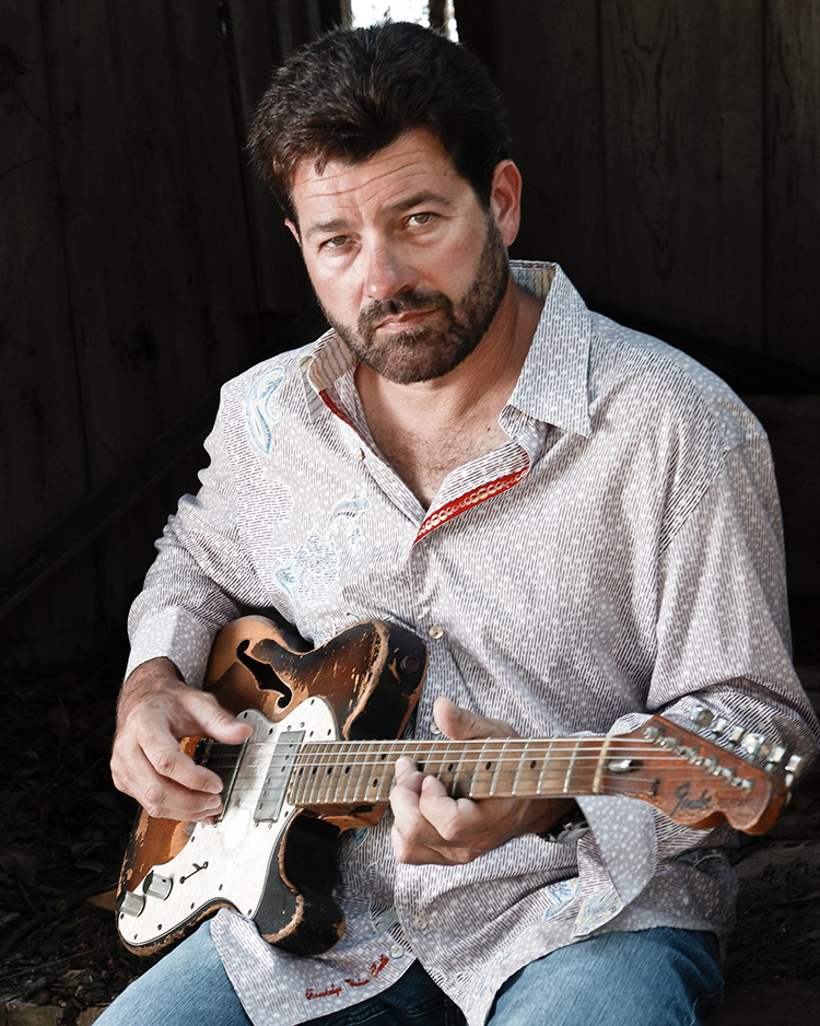 a person sitting and playing a guitar